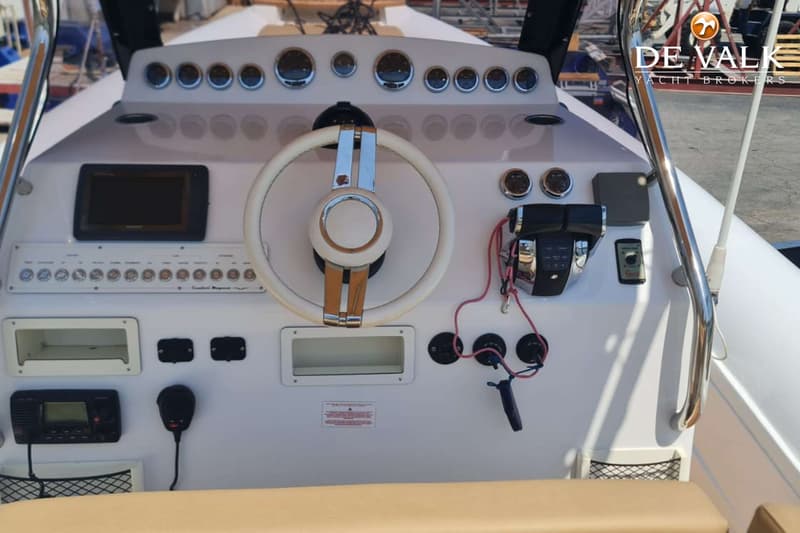 Een witte stuurconsole met een wit stuurwiel, diverse meters, een plotter, schakelaars en een marifoon.