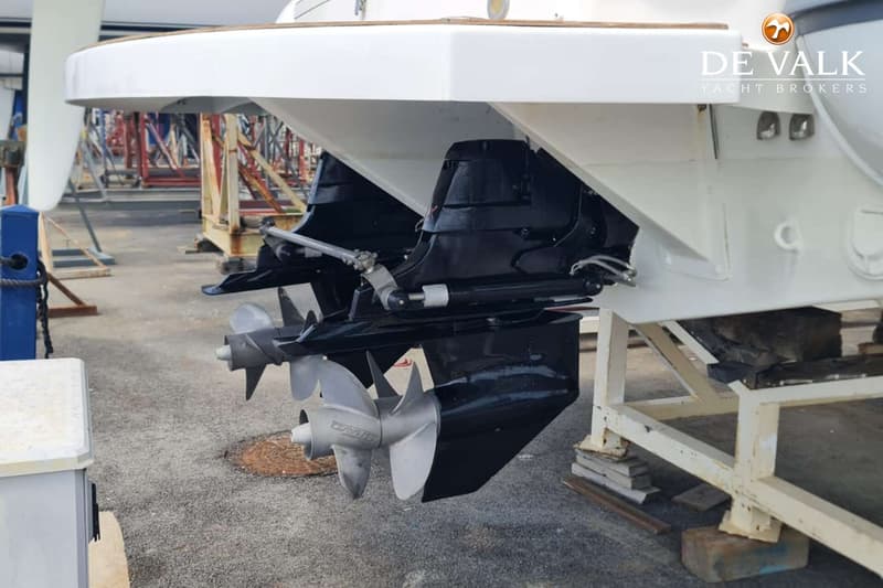 De foto toont de achterkant van een witte boot met twee zwarte buitenboordmotoren en zilverkleurige schroeven, staand op…