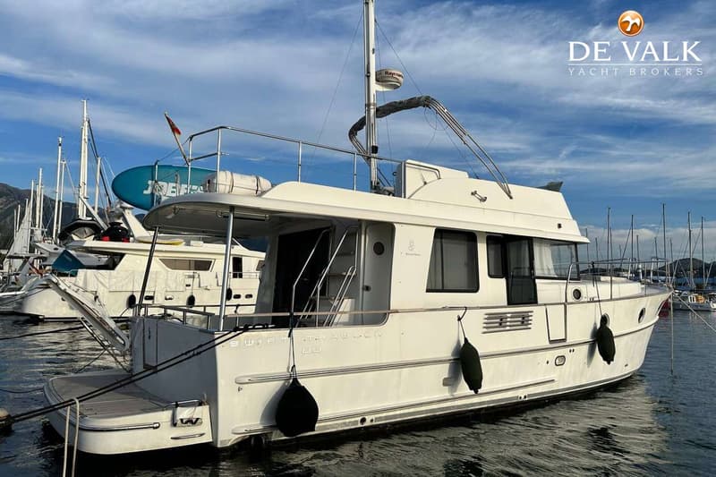 Een witte motorboot met de tekst "SWIFT TRAWLER 44" op de zijkant ligt aangemeerd in een haven. — Beneteau Swift Trawler 44