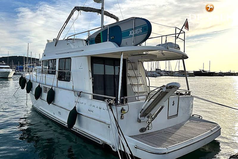 Een witte boot met de tekst "SWIFT TRAWLER 44" op de zijkant ligt aangemeerd in een haven. — Beneteau Swift Trawler 44