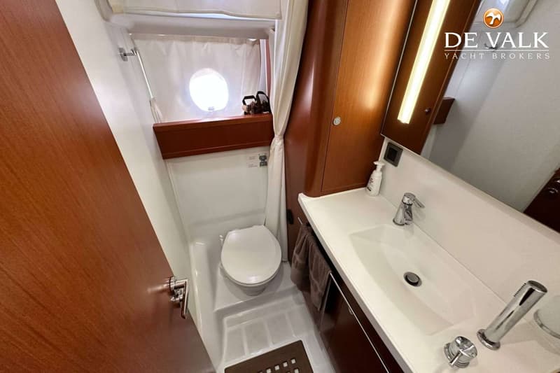 De foto toont een badkamer met een toilet, een wastafel met kraan en een spiegel met verlichting.