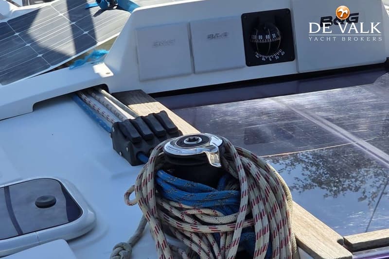 Een dek van een boot met een lier, touwen, zonnepanelen, een kompas en een logo van "DE VALK YACHT BROKERS". — Hanse 315
