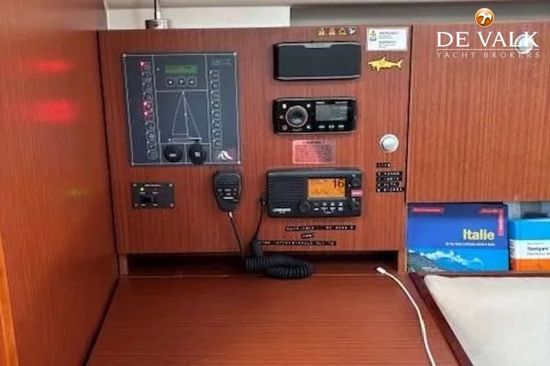 Een houten paneel met diverse elektronische apparatuur, waaronder een marifoon en een schakelpaneel met een…