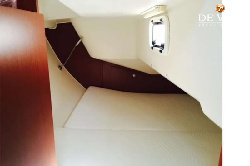 De foto toont een kajuit met een bed, een patrijspoort en houten en lichte wanden. — Hanse 315