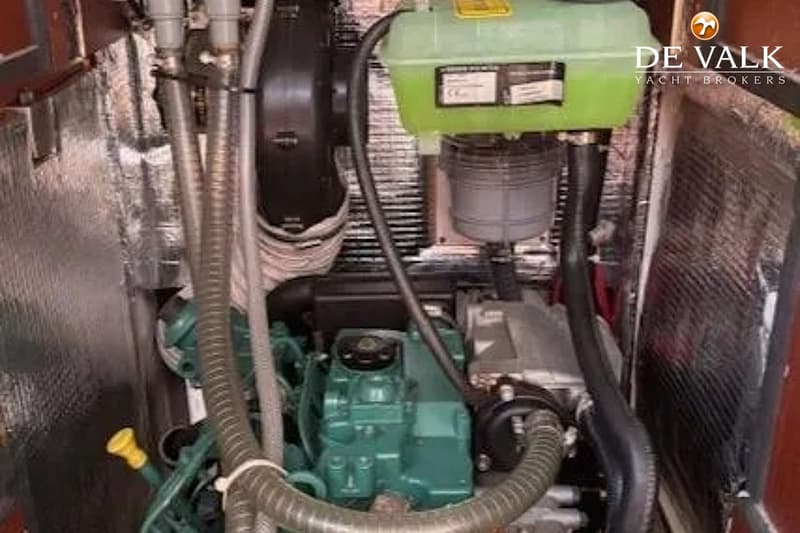 Een detailfoto van een motorruimte met een groene motor, diverse slangen en een groen reservoir.