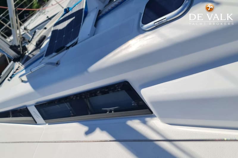 Een deel van een witte boot met ramen, een zonnepaneel en een mast is zichtbaar. — Hanse 315