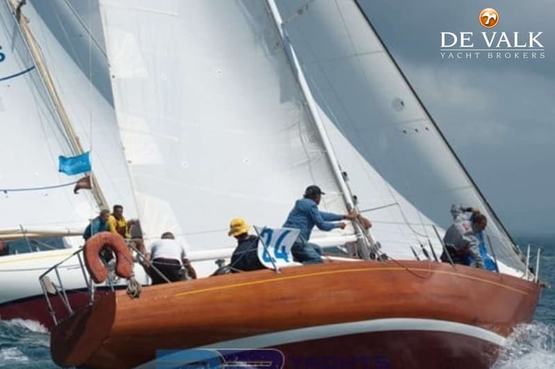 Een houten zeilboot met witte zeilen en meerdere bemanningsleden aan boord vaart op zee. — Sangermani 10.50