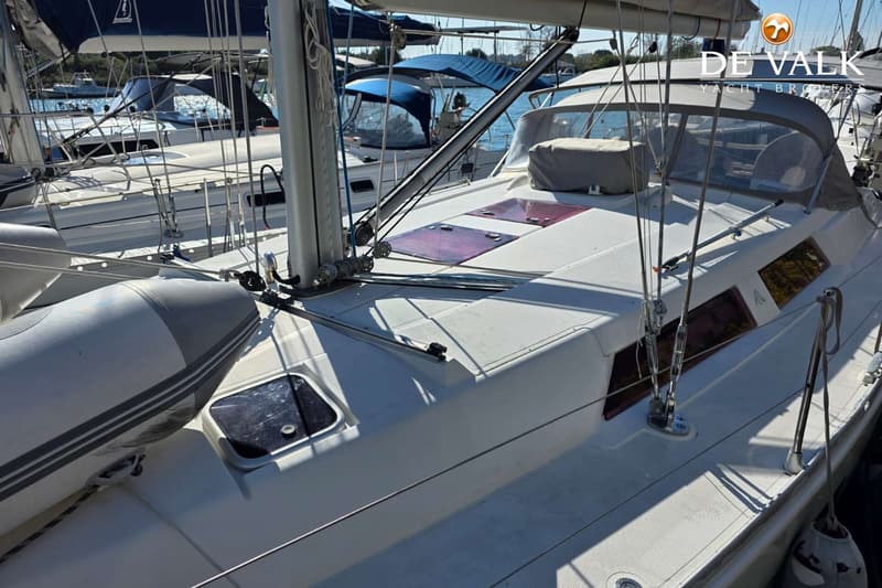 Een witte zeilboot met een grijze opblaasboot aan bakboord, liggend in een haven met andere boten. — Hanse 400e