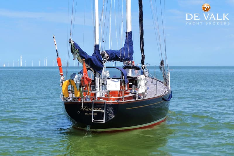 Een donkerblauwe zeilboot met de naam "Diotima" en "Hamburg" op de spiegel, ligt in het water. — Huisman 45