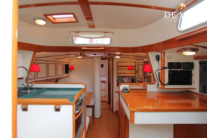 De foto toont het interieur van een boot met een kombuis, navigatiehoek en een doorgang naar een andere ruimte. — Huisman 45