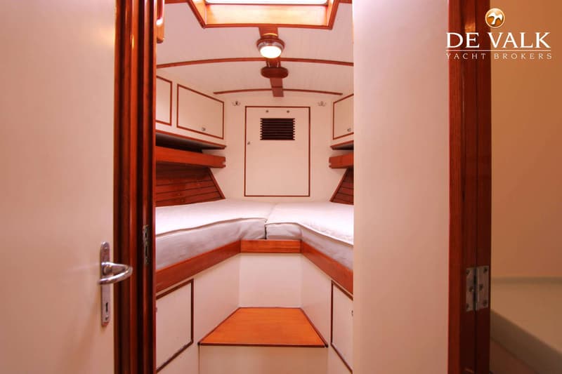 De foto toont het interieur van een boot met een kajuit met twee bedden, houten afwerking en een dakraam. — Huisman 45