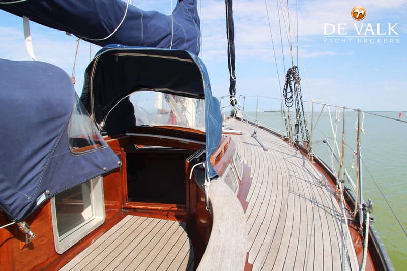 Een zeilboot met een teakdek, donkerblauwe buiskap en zeilhuik, en een open kajuitingang. — Huisman 45