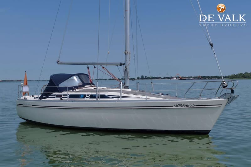 Een witte zeilboot met de naam "MORPHEUS" ligt in het water onder een helderblauwe lucht. — Moody 336