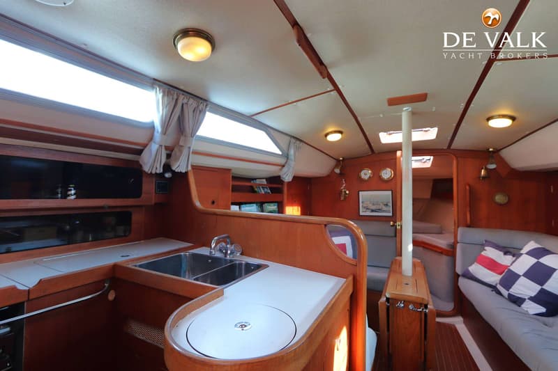 De foto toont het interieur van een boot met een kombuis, zitgedeelte en houten afwerking. — Moody 336