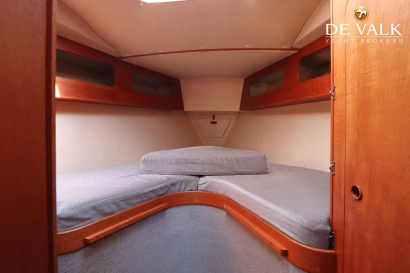 De foto toont een kajuit met een V-vormig bed met grijze matrassen en houten accenten. — Moody 336