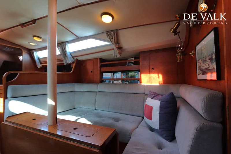 De foto toont het interieur van een boot met een U-vormige bank, houten lambrisering en een centrale mast. — Moody 336