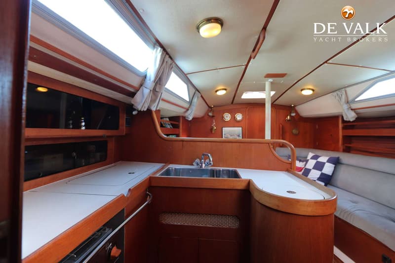 De foto toont een interieur van een boot met een kombuis aan de linkerkant en een zithoek aan de rechterkant. — Moody 336