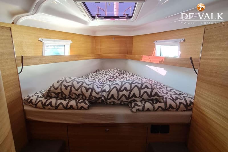 Een kajuit met een bed met hartjespatroon beddengoed, twee zijramen en een dakraam. — Elan Impression 45.1