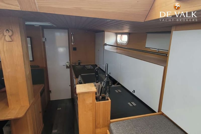 De foto toont een interieur van een boot met een kombuis, houten afwerking en een zithoek. — Custom Built Sloop