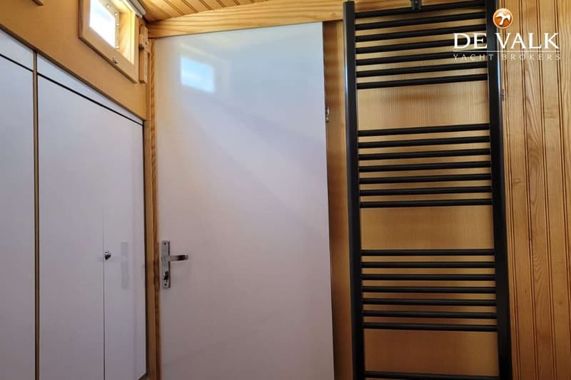 Een interieur met houten lambrisering, een witte deur, een witte kast en een zwarte handdoekradiator.