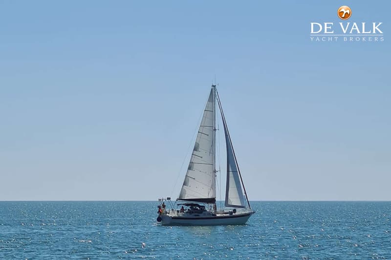 Een zeilboot met twee zeilen is te zien op open water onder een helderblauwe lucht. — Custom Built Sloop