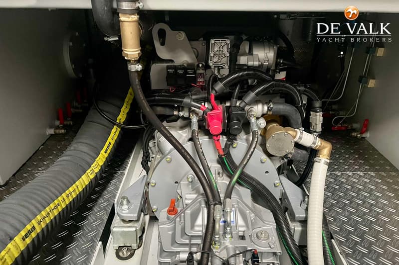Een close-up van een scheepsmotor met diverse slangen, kabels en leidingen.
