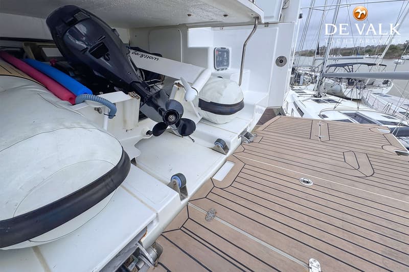 Een opblaasboot met buitenboordmotor en zwemnoodels in een opbergruimte aan boord van een jacht met teakhouten dek.