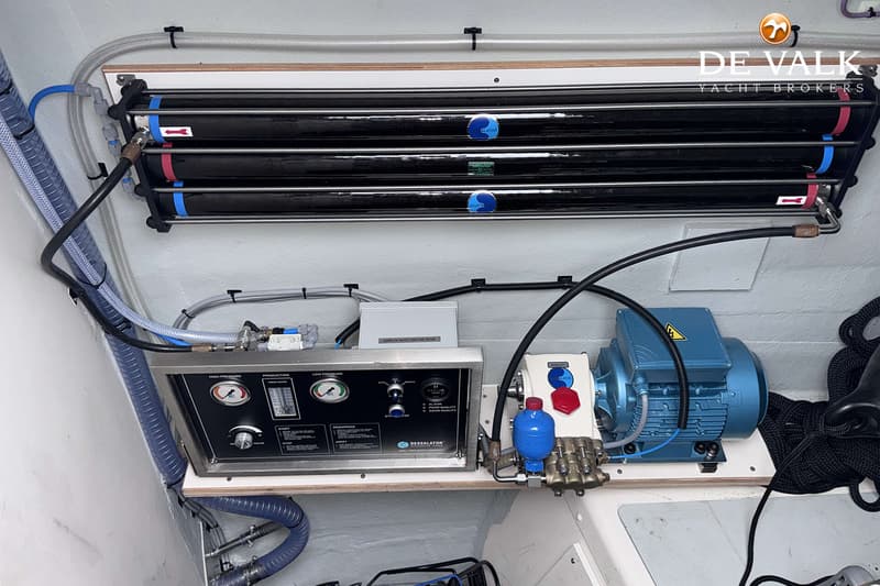 Een detailfoto van een watermaker met drie zwarte filters, een bedieningspaneel en een blauwe motor.