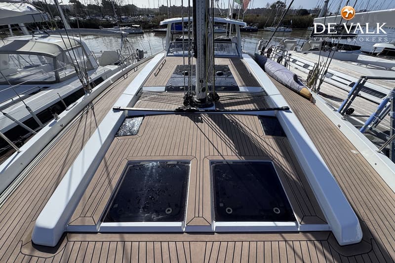 Een bovenaanzicht van het dek van een zeilboot met een mast, twee grote luiken en een houten dek. — Hanse 588