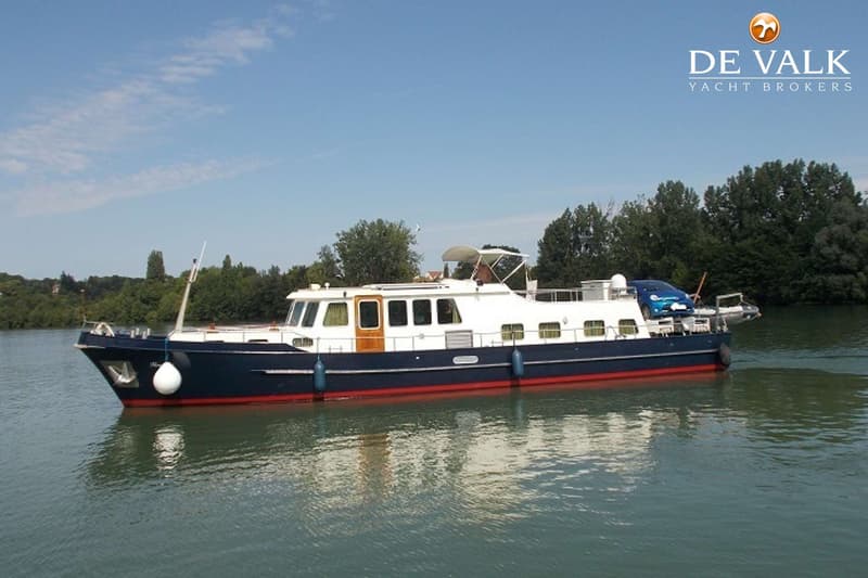 Een blauw-witte motorboot met een rode streep vaart op een waterweg met bomen op de achtergrond. — Tin Line 65