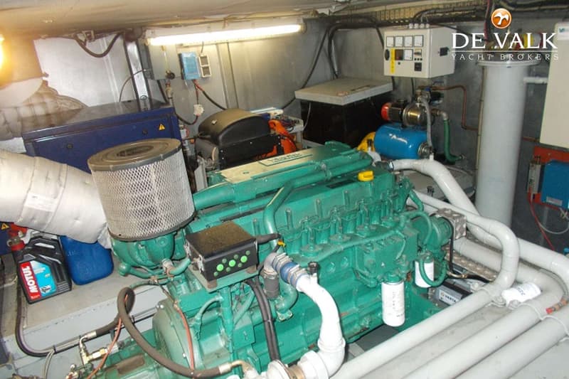 Een groene scheepsmotor met diverse leidingen, filters en een bedieningspaneel in een machinekamer.