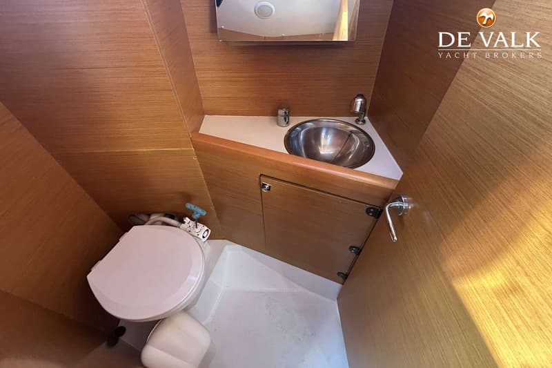 Een toiletruimte met een wit toilet, een zilveren wasbak en houten wanden.