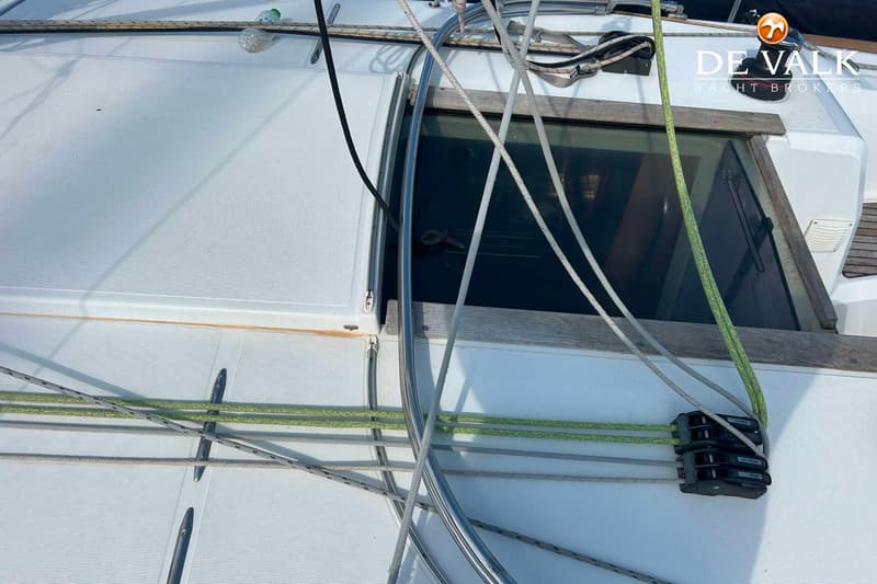 Een detailfoto van het dek van een zeilboot met touwen, een raam en een lier. — Jeanneau Sun Odyssey 349