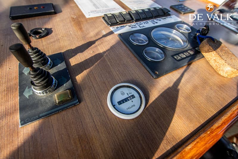 Een close-up van een houten dashboard met diverse meters, schakelaars en bedieningshendels, inclusief een urenteller.