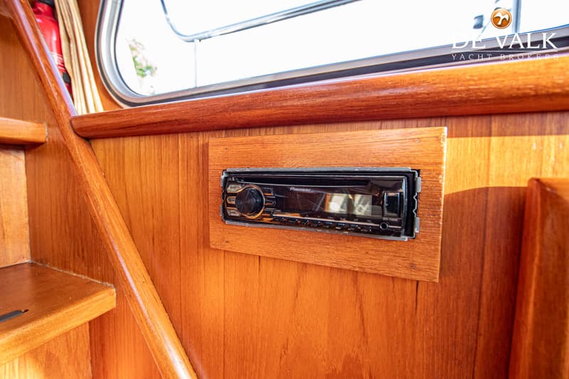 Een Pioneer autoradio is ingebouwd in een houten paneel, met een trap en een raam op de achtergrond.