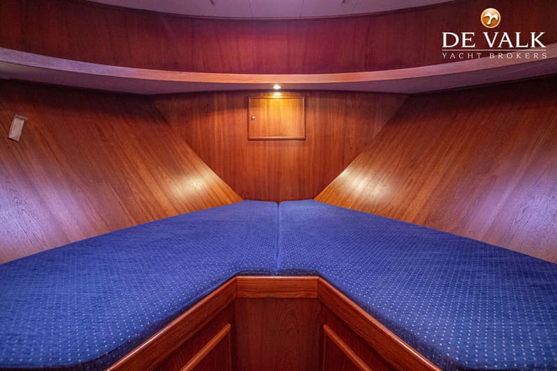 Een kajuit met houten wanden en twee blauwe kussens die een V-vormig bed vormen. — De Drait Deluxe 42