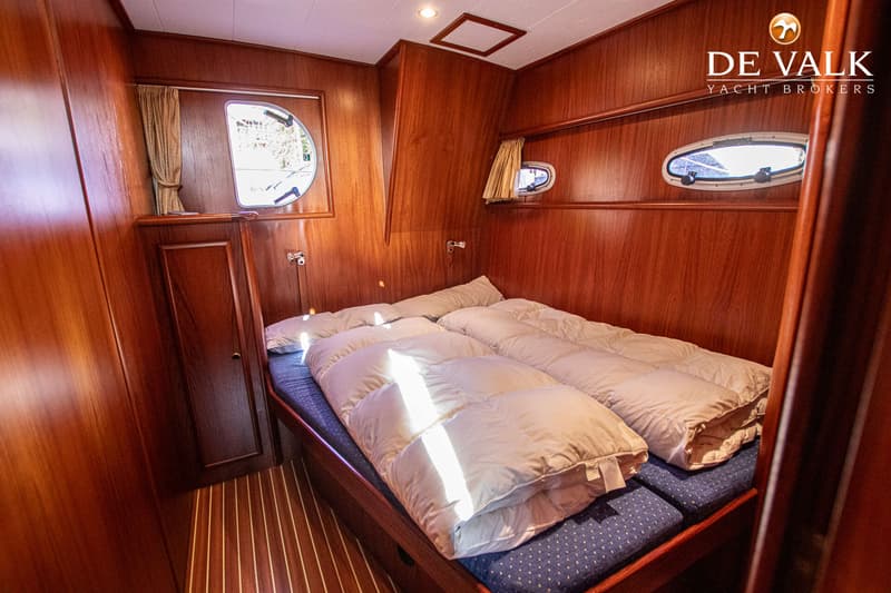 Een kajuit met twee eenpersoonsbedden, houten wanden en een patrijspoort met gordijn. — De Drait Deluxe 42
