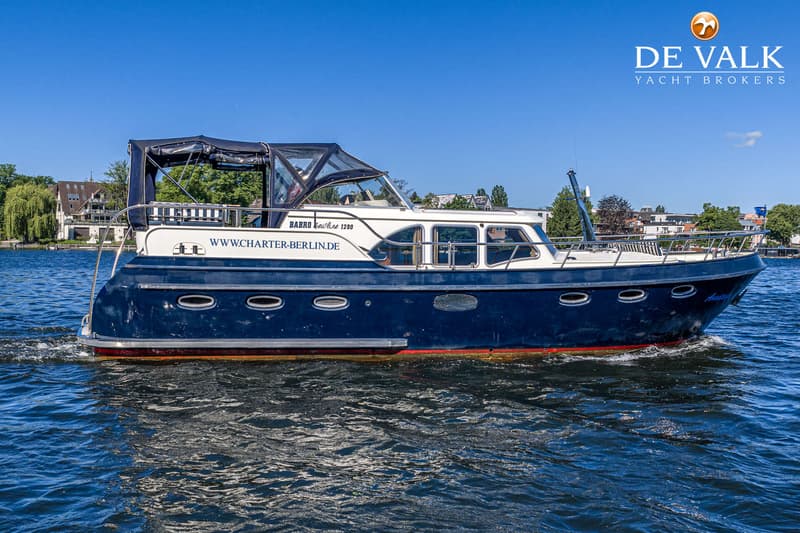 Een blauw-witte motorboot met een zwarte kap vaart op een zonnige dag over het water. — Babro Newline 1290