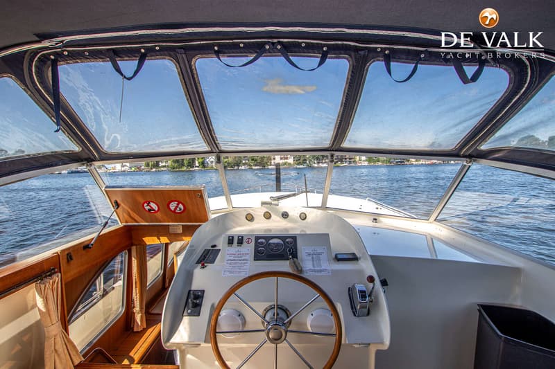 De foto toont het interieur van een boot met een stuurwiel en een dashboard, uitkijkend over water. — Babro Newline 1290