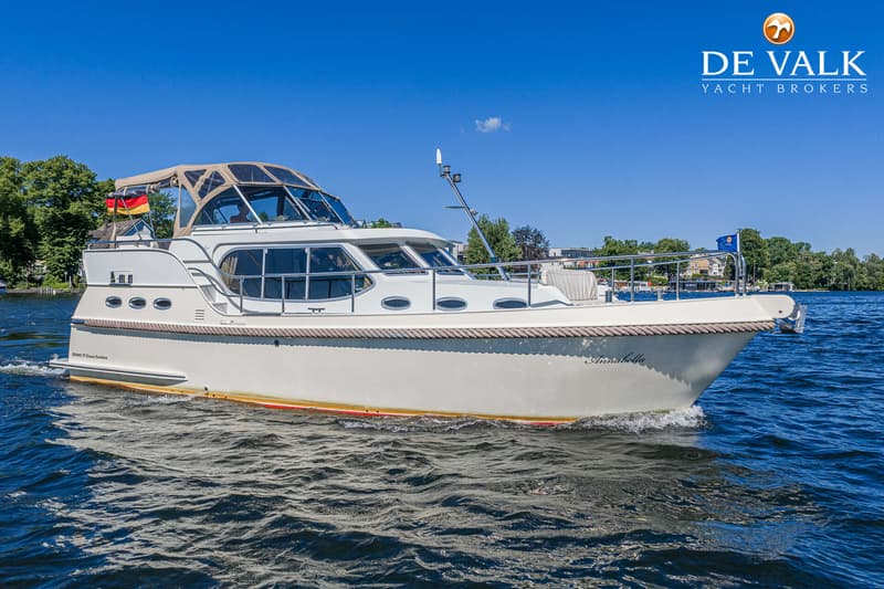 Een witte motorboot met een beige cabriokap vaart op blauw water onder een heldere hemel. — Gruno 37 Classic