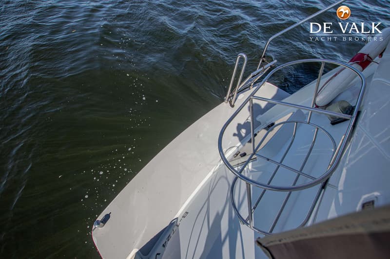 Een bovenaanzicht van de achtersteven van een boot met een zwemplateau en een reddingsboei, omringd door water.