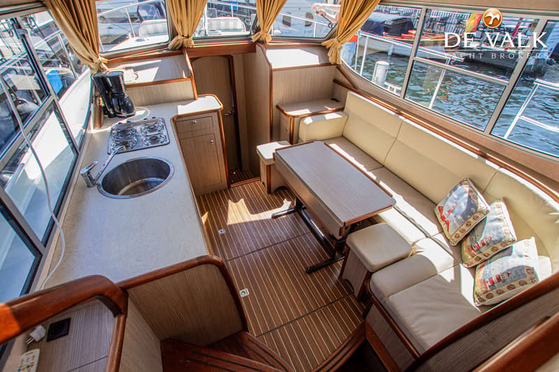 De foto toont het interieur van een boot met een keukenblok, zithoek, tafel en houten vloer. — Gruno 37 Classic