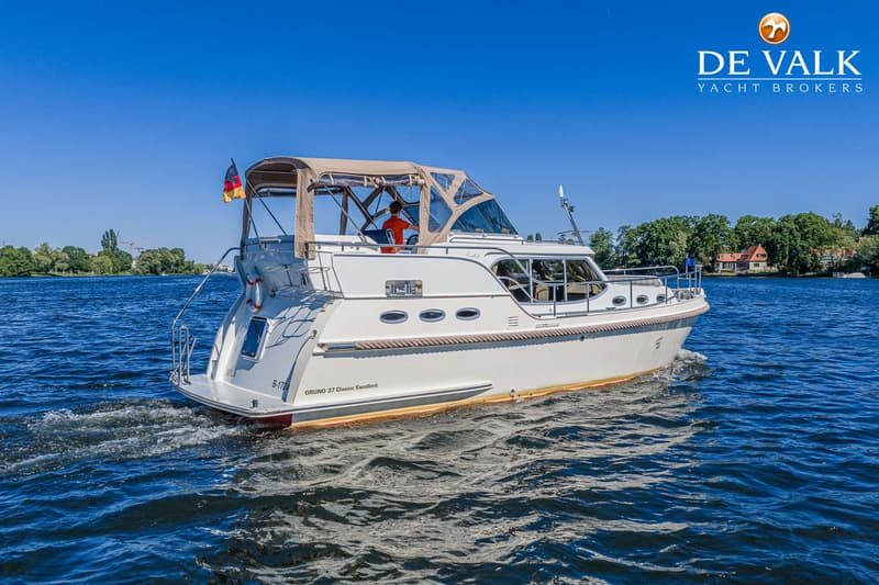 Een witte motorboot met een beige cabriokap vaart op blauw water onder een heldere hemel. — Gruno 37 Classic
