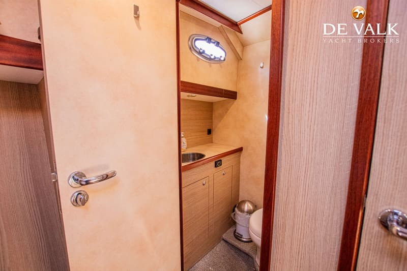 Een interieurfoto van een badkamer met een wastafel, een toilet en een patrijspoort.