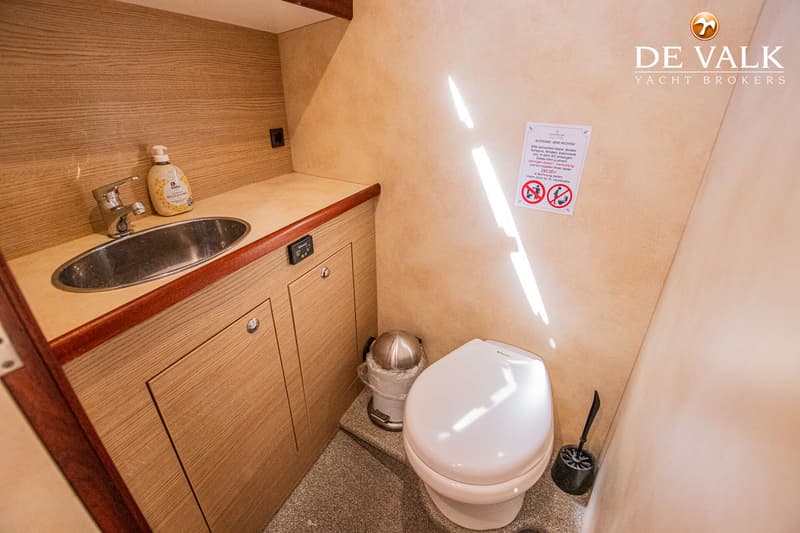 Een badkamer met een wastafel, toilet, prullenbak en een toiletborstel.