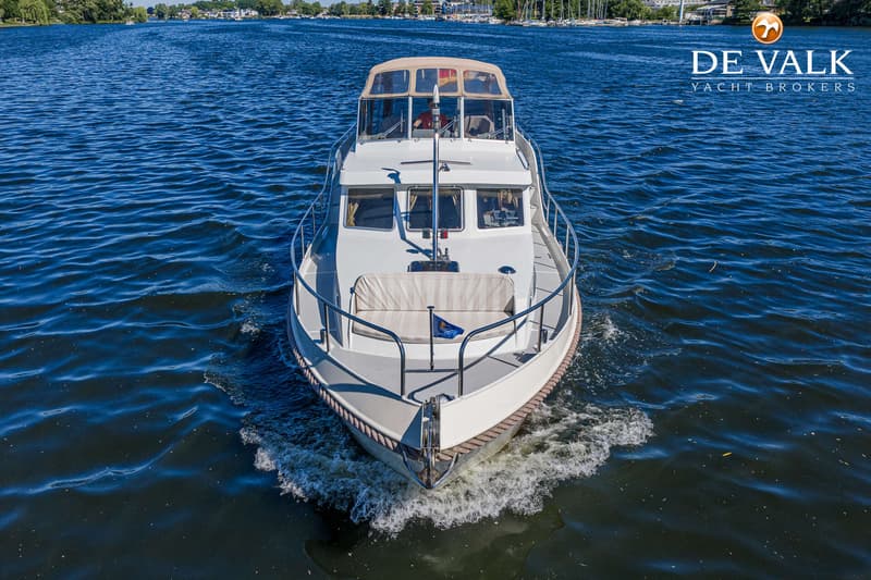 Een witte motorboot met een beige kap vaart op blauw water, gezien vanaf de voorkant. — Gruno 37 Classic