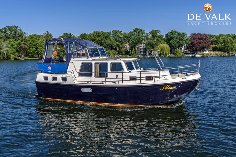 Een donkerblauwe motorboot met een witte opbouw en een blauwe kap vaart op rustig water. — Pedro Marin 30