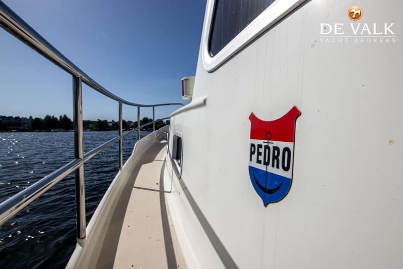Een witte boot met een rood, wit en blauw Pedro-embleem op de zijkant vaart op een zonnige dag. — Pedro Marin 30