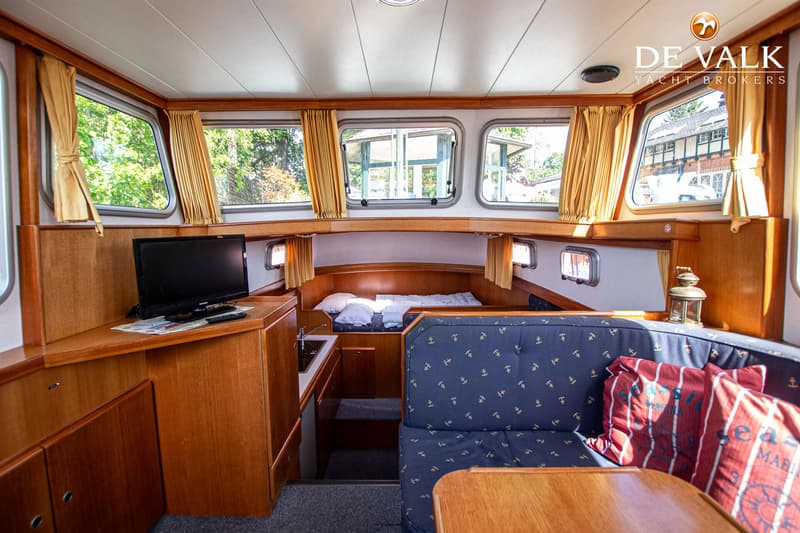 De foto toont het interieur van een boot met een zithoek, een bed, een kleine keuken en een televisie. — Pedro Marin 30