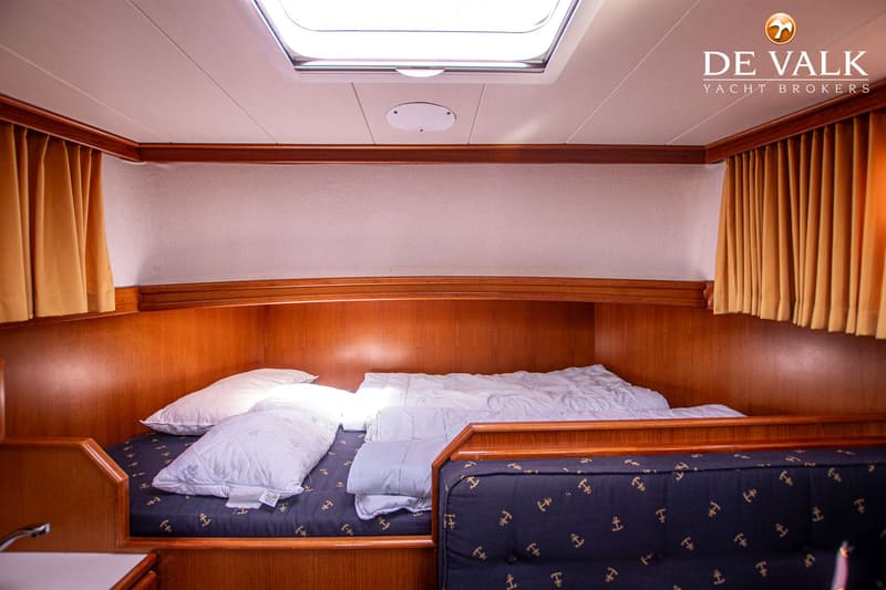 Een kajuit met een bed met twee kussens en een dekbed, en een bank met ankerpatroon. — Pedro Marin 30